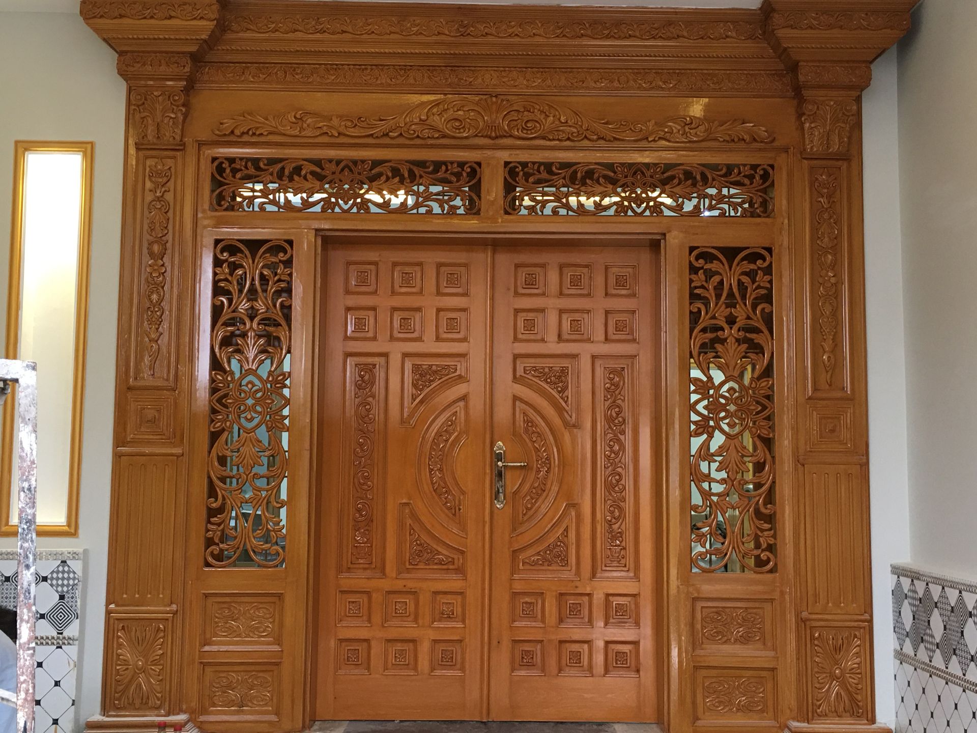 This image showcases a beautifully designed wooden door, featuring intricate carvings and a polished finish that adds a touch of sophistication to any home entrance. Wooden doors are popular for their durability, classic appeal, and versatility in design. From rustic and traditional to modern and minimalist styles, these designs offer a range of options to suit various architectural aesthetics